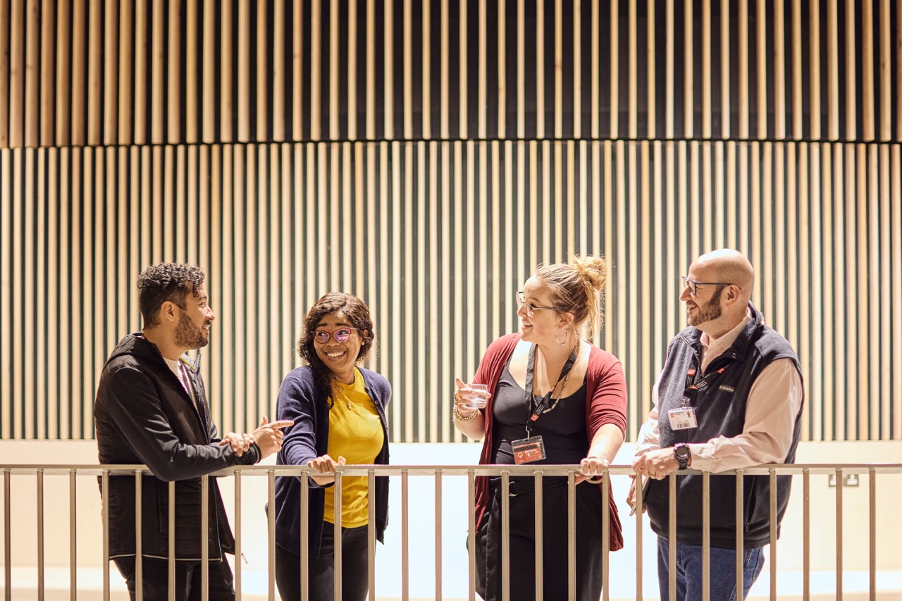 Four LSE Marshall Institute students chatting outside a classroom in the Marshall building