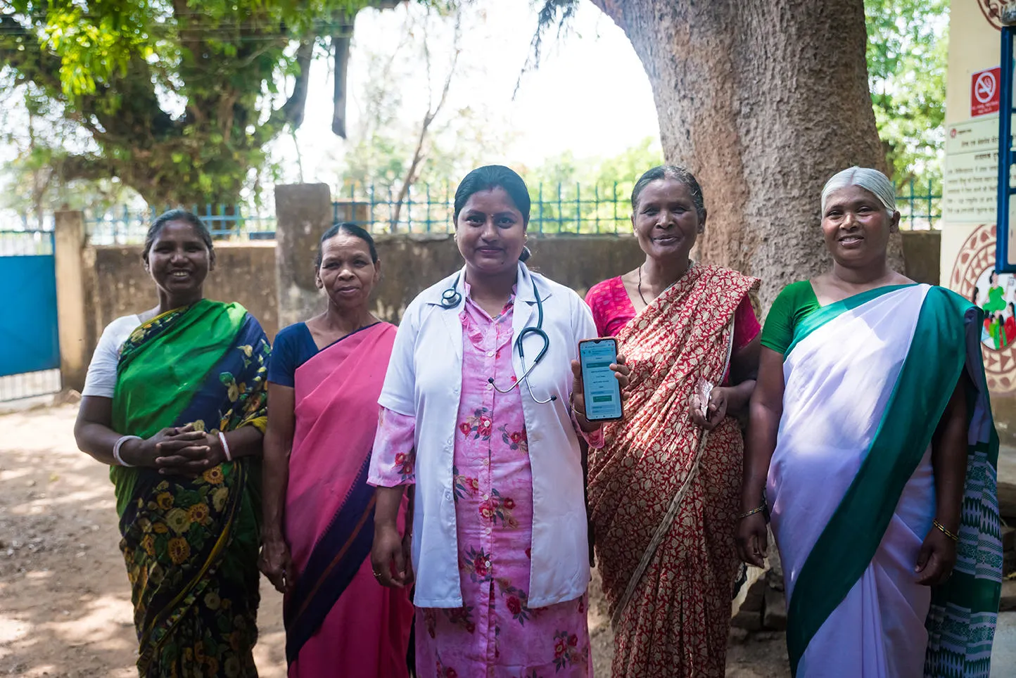 Women standing with a doctor holding a phone